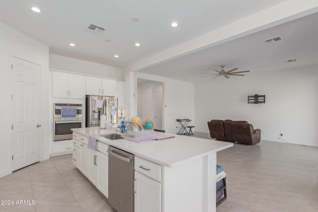 kitchen with appliances with stainless steel finishes, ceiling fan, a center island with sink, and white cabinetry