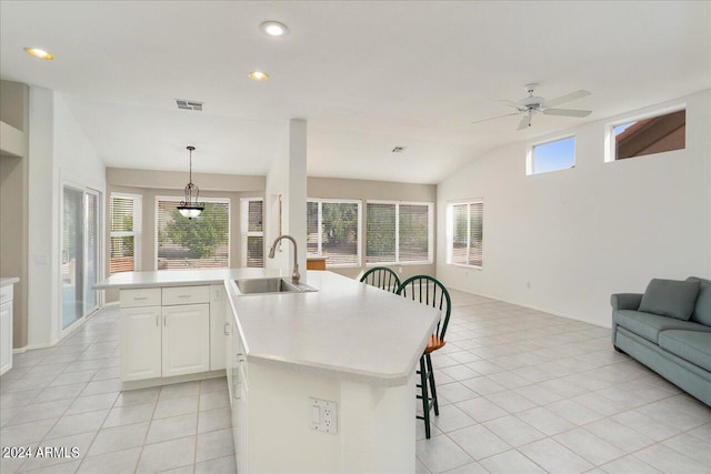 kitchen featuring an island with sink, pendant lighting, ceiling fan with notable chandelier, and sink