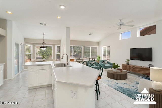 kitchen with decorative light fixtures, ceiling fan with notable chandelier, sink, white cabinetry, and a kitchen island with sink