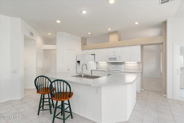 kitchen with tasteful backsplash, white cabinets, a breakfast bar area, white appliances, and light tile flooring