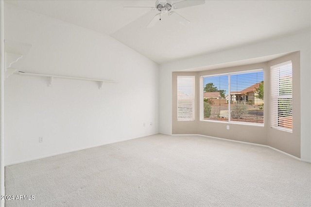 carpeted spare room featuring vaulted ceiling and ceiling fan