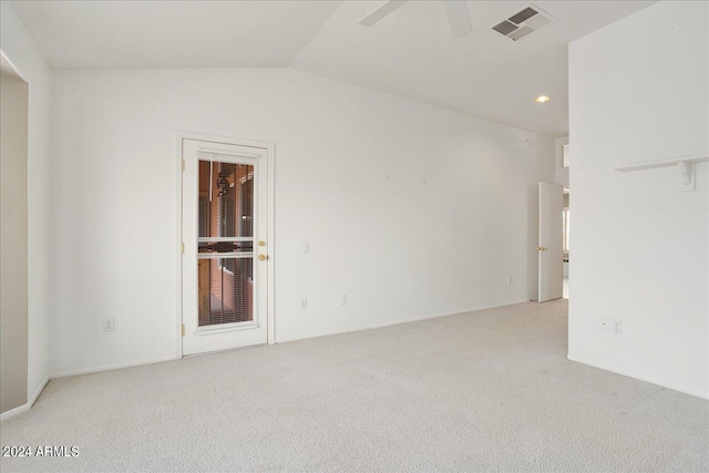 empty room with ceiling fan, vaulted ceiling, and light colored carpet