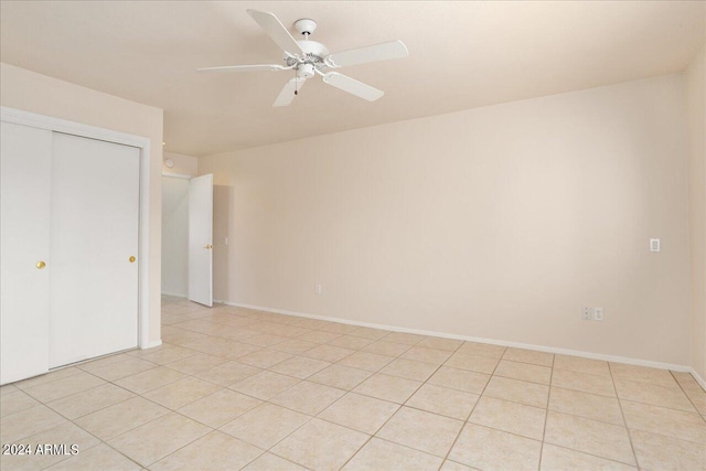 unfurnished bedroom with light tile floors, a closet, and ceiling fan