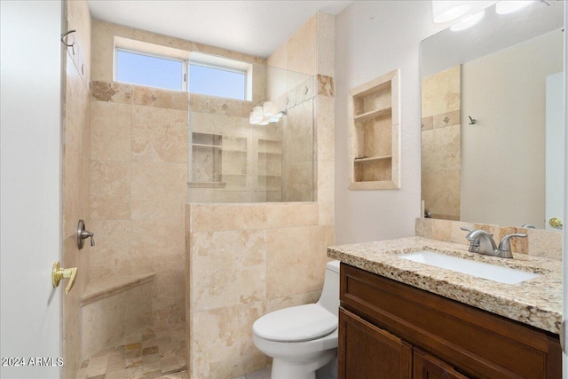 bathroom featuring a tile shower, oversized vanity, toilet, and tile walls