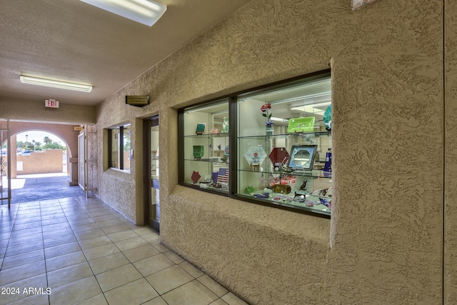 corridor with a textured ceiling and light tile flooring