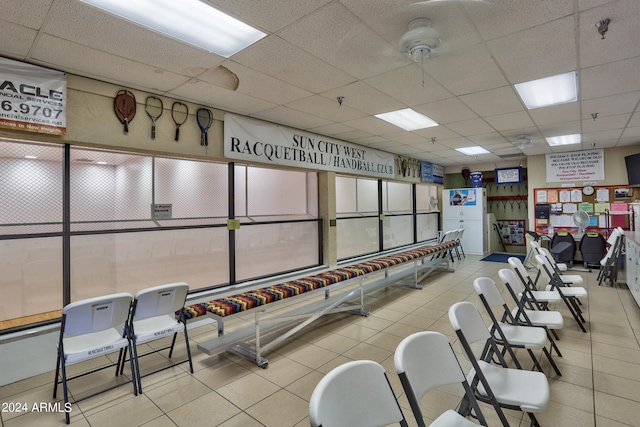 exercise room with a paneled ceiling and light tile flooring