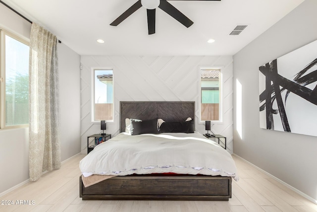 bedroom featuring ceiling fan, light hardwood / wood-style flooring, and multiple windows