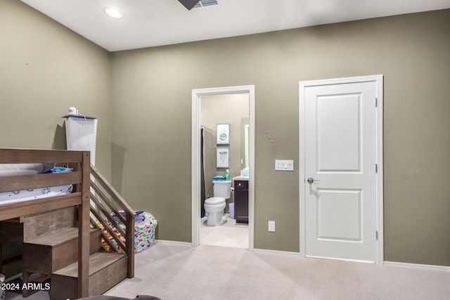 bedroom with ensuite bathroom and light carpet