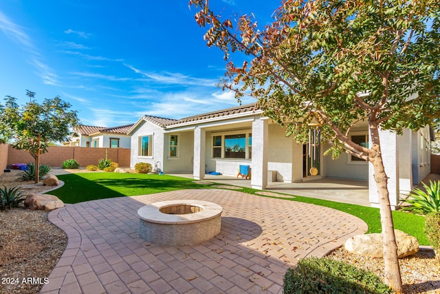 rear view of property with a patio area, a yard, and a fire pit