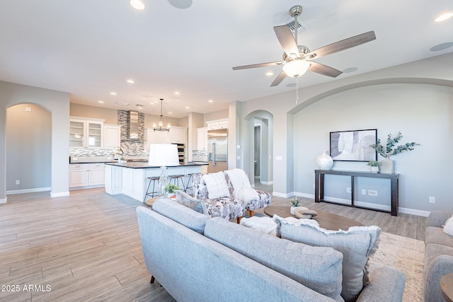 36169 N Serrano Ave, Queen Creek, AZ 85140 - living area with baseboards, arched walkways, light wood-style floors, recessed lighting, and ceiling fan with notable chandelier