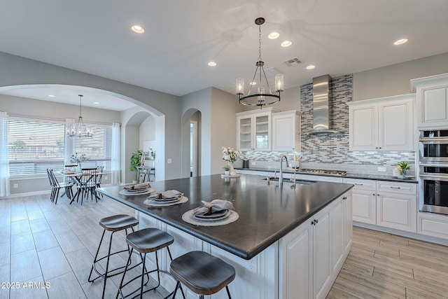 36169 N Serrano Ave, Queen Creek, AZ 85140 - kitchen featuring a chandelier, arched walkways, wall chimney exhaust hood, and dark countertops