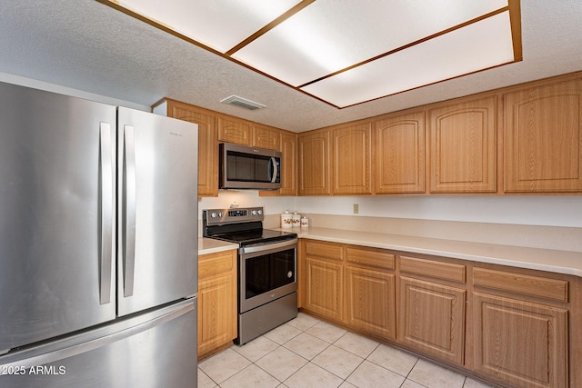 kitchen featuring light tile patterned flooring, stainless steel appliances, and a textured ceiling