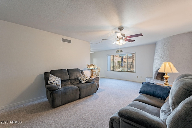 carpeted living room featuring ceiling fan and a textured ceiling