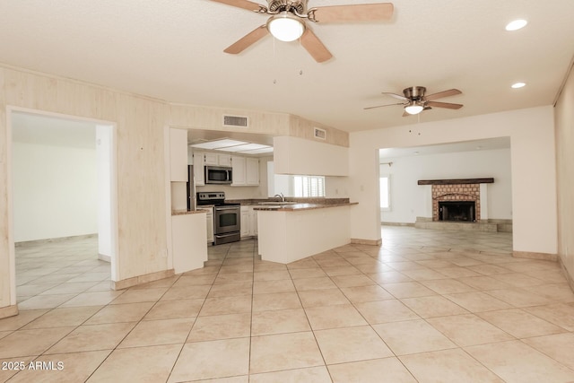 kitchen with visible vents, white cabinets, open floor plan, a peninsula, and stainless steel appliances