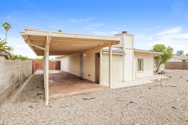 exterior space featuring an attached carport, a fenced backyard, and central AC unit