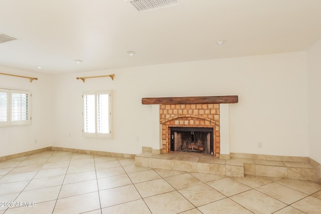 unfurnished living room featuring light tile patterned floors, baseboards, visible vents, and a fireplace with raised hearth