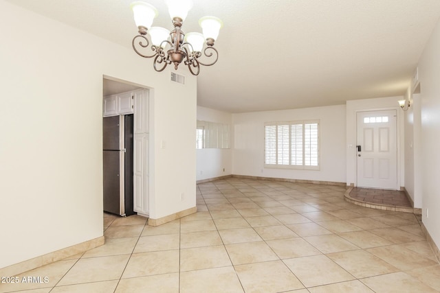 interior space with light tile patterned floors, baseboards, visible vents, and a chandelier