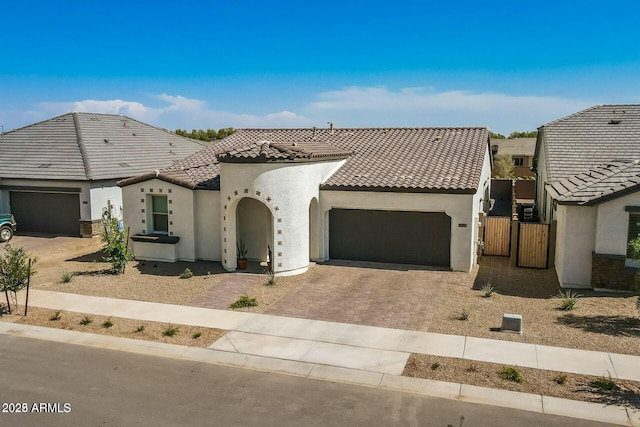 view of front of property featuring a tiled roof, decorative driveway, a garage, and stucco siding