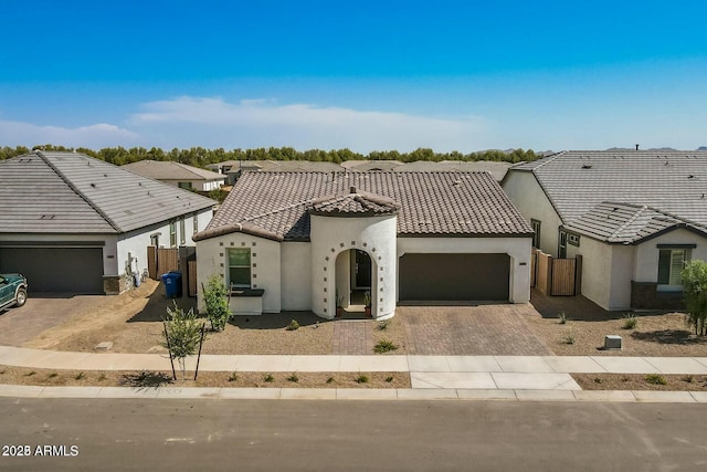 view of front of property with stucco siding, decorative driveway, fence, an attached garage, and a tiled roof