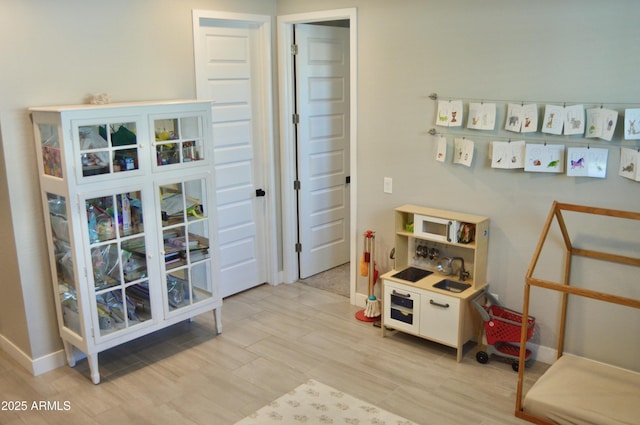 game room with light wood-style flooring and baseboards