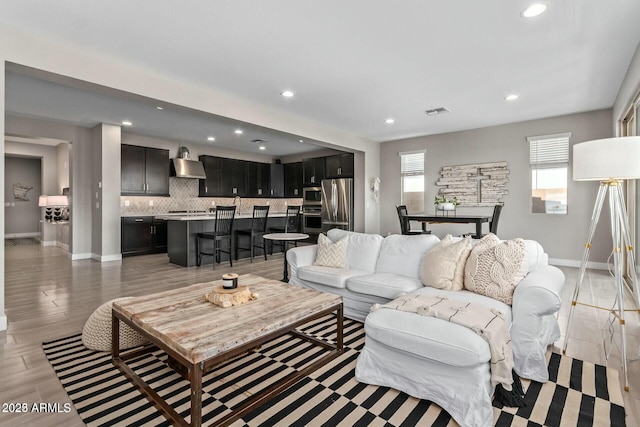 living area with visible vents, recessed lighting, light wood-style floors, and baseboards