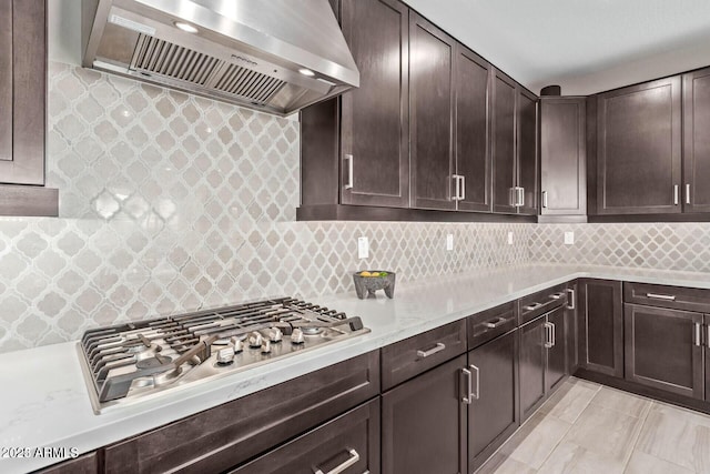 kitchen with stainless steel gas cooktop, decorative backsplash, dark brown cabinets, and extractor fan