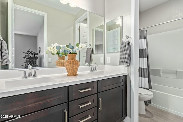 bathroom featuring a sink, shower / tub combo, toilet, and double vanity