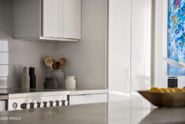 room details with tasteful backsplash, gas stovetop, and white cabinets