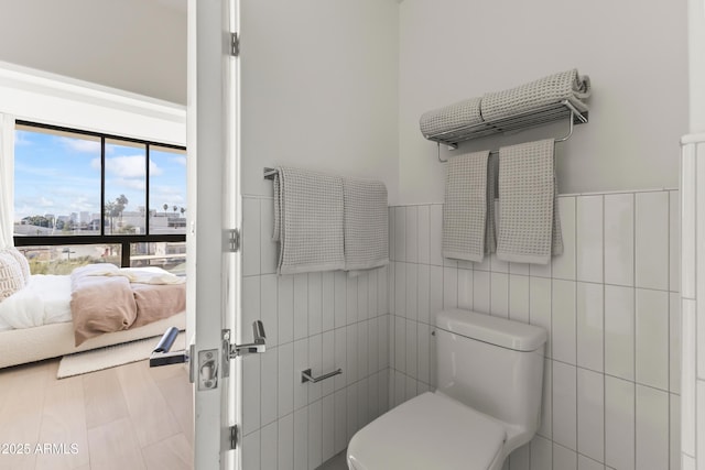 ensuite bathroom with wainscoting, toilet, ensuite bath, a city view, and tile walls