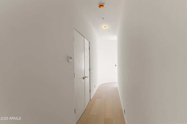 hall featuring light wood-type flooring and baseboards