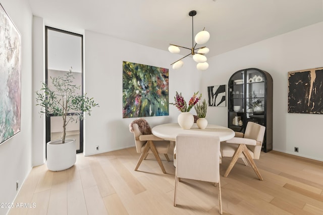 dining area with baseboards, light wood-style flooring, and a notable chandelier