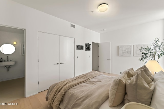 bedroom with sink, light hardwood / wood-style flooring, and a closet