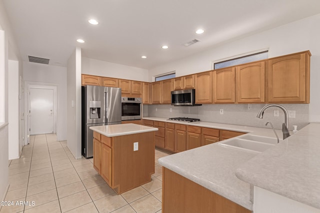 kitchen with light tile patterned floors, stainless steel appliances, decorative backsplash, a center island, and sink