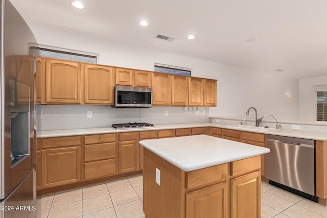 kitchen featuring a center island, decorative backsplash, sink, stainless steel appliances, and light tile patterned floors