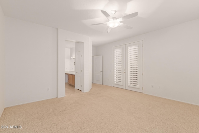 unfurnished bedroom featuring ceiling fan, light colored carpet, and ensuite bath