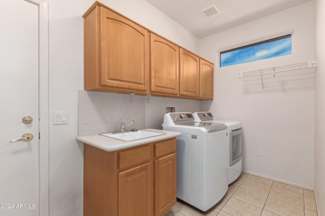 washroom with light tile patterned floors, independent washer and dryer, sink, and cabinets