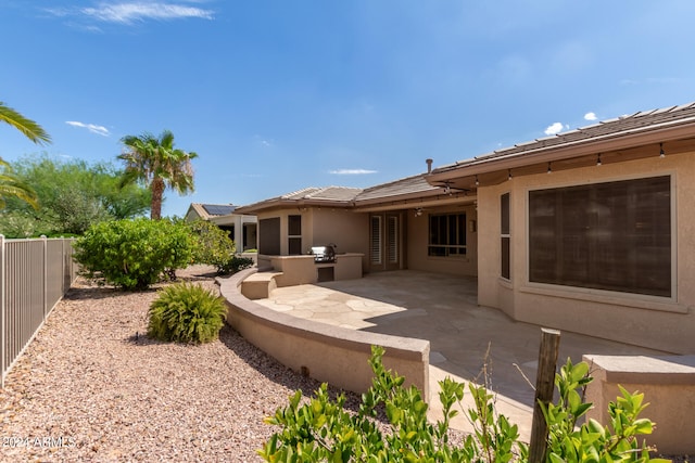 rear view of property featuring an outdoor kitchen and a patio area