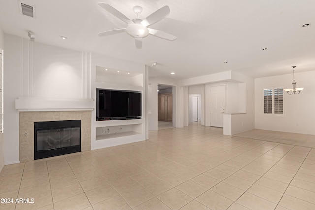 unfurnished living room featuring ceiling fan with notable chandelier, light tile patterned floors, built in features, and a tiled fireplace