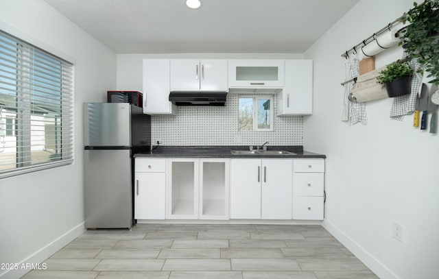 kitchen with white cabinetry, stainless steel fridge, sink, and decorative backsplash