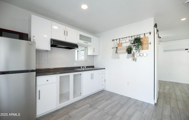 kitchen with sink, extractor fan, white cabinetry, stainless steel fridge, and backsplash