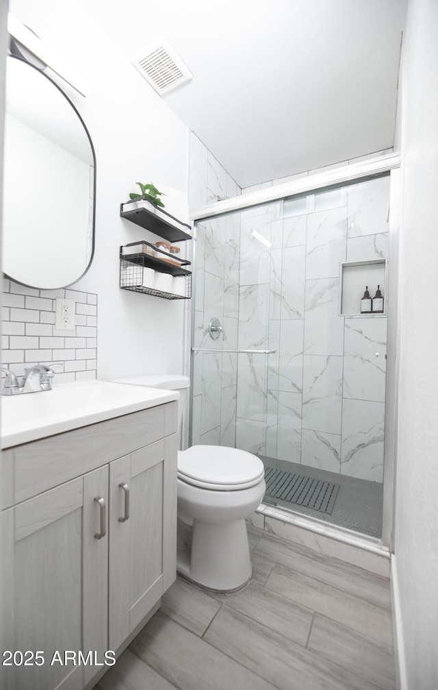 bathroom with tasteful backsplash, vanity, a shower with shower door, and toilet