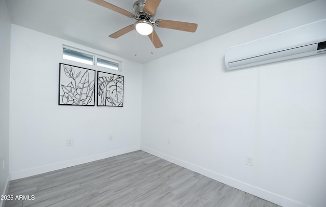 spare room with a wall mounted air conditioner, light hardwood / wood-style flooring, and ceiling fan