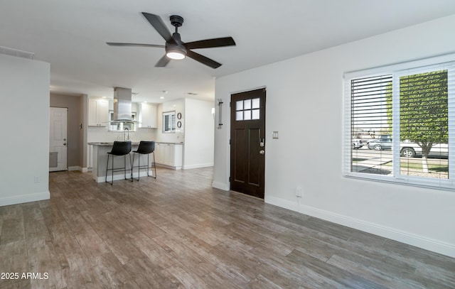 unfurnished living room featuring ceiling fan, wood-type flooring, and a healthy amount of sunlight