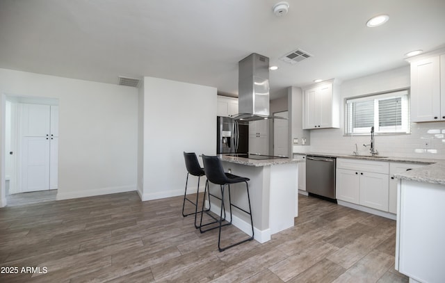 kitchen with a kitchen island, sink, white cabinets, island exhaust hood, and stainless steel appliances