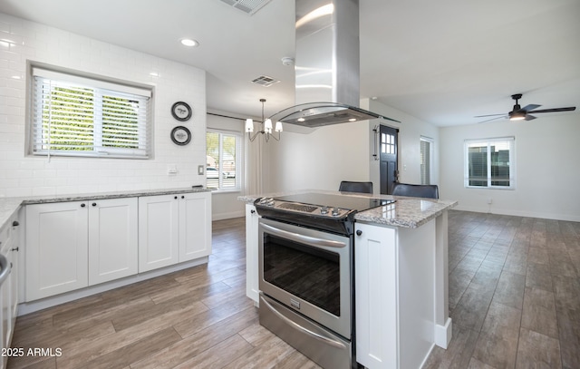 kitchen featuring electric stove, light stone counters, white cabinetry, and island exhaust hood