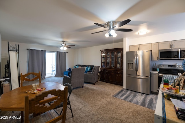 dining area with ceiling fan and dark colored carpet