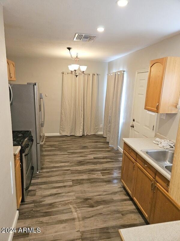 kitchen featuring gas range, dark hardwood / wood-style floors, an inviting chandelier, hanging light fixtures, and sink