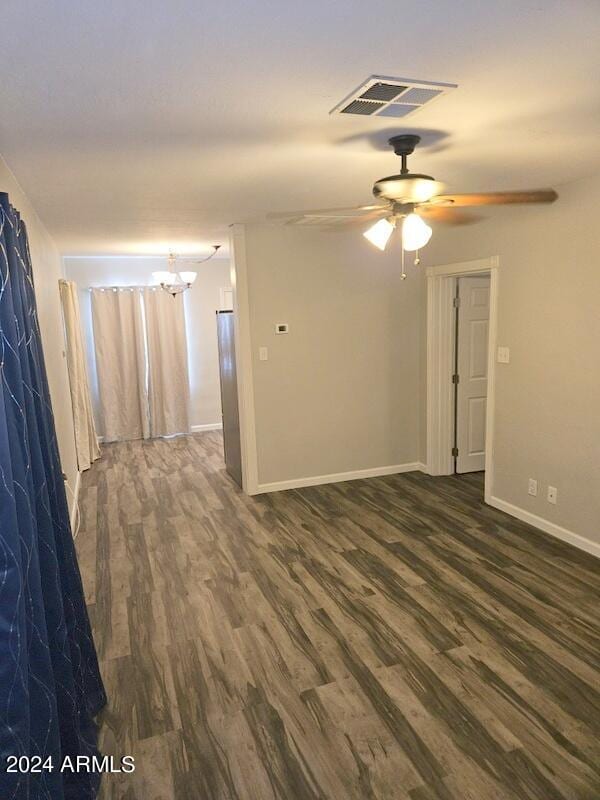 empty room featuring dark hardwood / wood-style floors and ceiling fan with notable chandelier