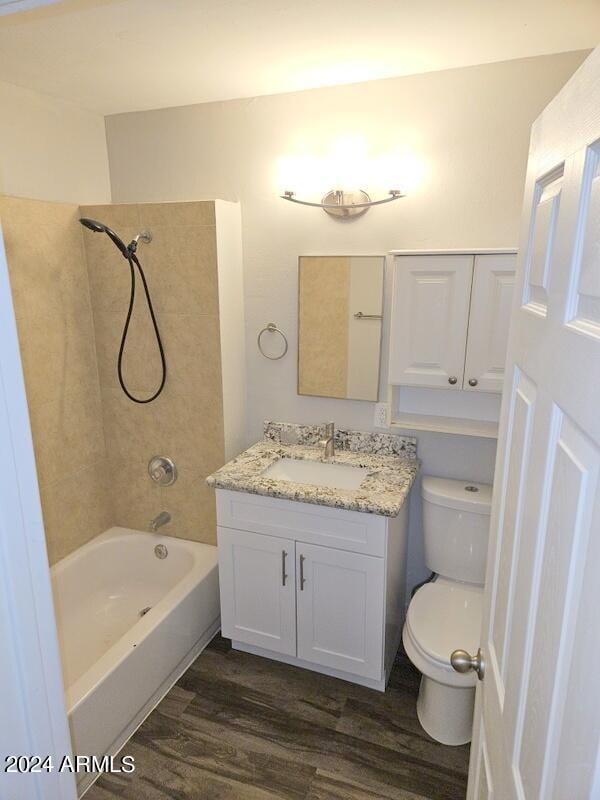 full bathroom featuring hardwood / wood-style floors, toilet, tiled shower / bath combo, and vanity