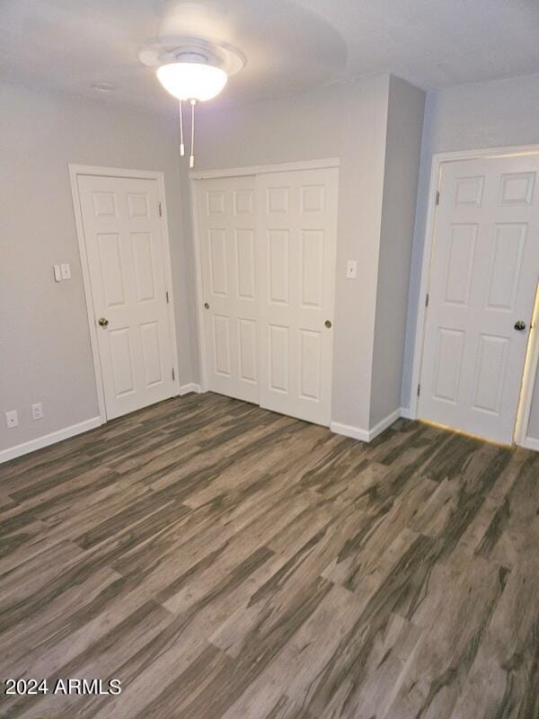 unfurnished bedroom with dark wood-type flooring and a closet